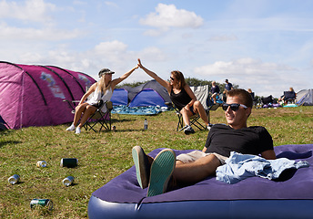 Image showing Man, relax and mattress at outdoor festival with happiness, camping and sunshine on grass. Guy, happy and women friends with high five, smile and support for summer, camp and party, event or carnival