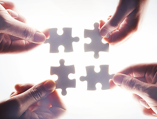 Image showing Hands, puzzle and flare with a business team working together on project planning closeup from below. Teamwork, collaboration or synergy and employee group with a jigsaw for strategy or innovation