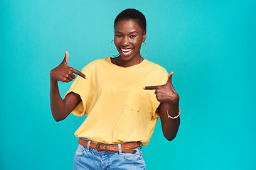 Image showing Portrait, crazy and pointing with a black woman in studio on a blue background looking carefree or silly. Smile, fashion and fun with a happy young female hipster feeling confident or playful