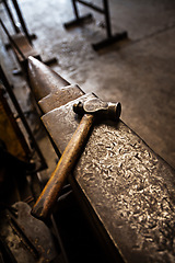 Image showing Hammer, anvil and blacksmith workplace in a iron factory and industrial workshop. Tools, metal work and steel artisan bench with craftmanship equipment to forge in warehouse with metals and materials