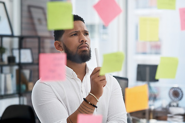 Image showing Serious man, thinking and brainstorming notes of business, solution, strategy and mindmap at glass window. Focused face of male worker planning schedule, problem solving and ideas for project goals