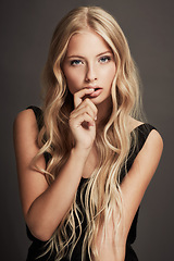 Image showing Beauty, face and portrait of a seductive woman with makeup, cosmetics and long hair in studio. Sexy female aesthetic model with skin glow, luxury skincare and finger in mouth on a grey background