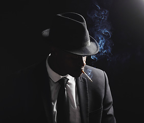 Image showing Man, gangster and cigarette in studio by black background with smoke, silhouette and dangerous in shadow. Mafia, secret agent or male in night for smoking with vintage aesthetic by dark backdrop