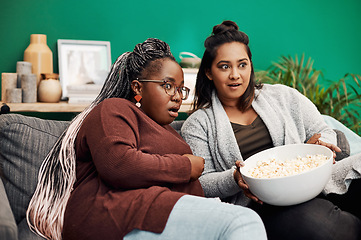 Image showing Girl friends, scary movie and home living room surprised on a couch with fear and shock. Series, tv and women together in a lounge with a female friend looking at a television in house with popcorn