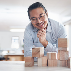 Image showing Design, strategy and portrait of man with building blocks in office, thinking and innovation for balance with smile. Engineering, challenge and asian designer with wood block game for problem solving