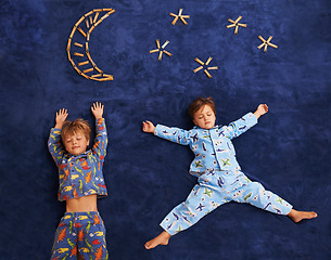 Image showing Boy kids in pajamas, sleeping on carpet with moon and stars design, top view and young children dreaming. Peace, calm and tired brothers or friends sleep on galaxy art on mat at family home