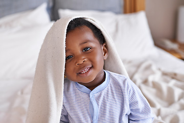 Image showing Portrait, happy and baby with a blanket in bed, waking up and playing in his home. Face, smile and african boy toddler in a bedroom curious, having fun and sweet, cute and playful while relaxing