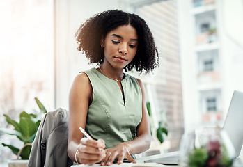 Image showing Corporate, black business woman writing in book and at laptop sitting at desk in her office. Planning schedule, reminder and focused African female worker in workplace write notes on information