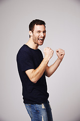 Image showing Winner, celebration and man cheer with success in studio for good news, winning and achievement. Celebrate, happy and excited male person on white background for victory, announcement and cheering