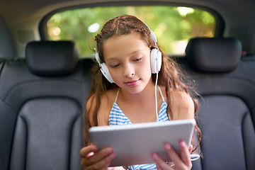 Image showing Technology, young girl in car with tablet and headphones while travelling. Social media or streaming, internet connectivity and child on road trip on vacation in vehicle with digital or mobile device