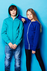 Image showing Fashion, portrait and young girl and boy in a studio with a casual, cool and stylish outfit. Youth, friendship and portrait of teenager models posing together with trendy style by a blue background.