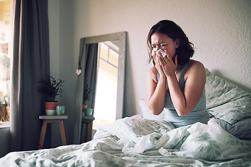 Image showing Home, tissue and woman with the flu, allergy and sick in her apartment, couch and suffering. Female person, blowing nose or girl in her bedroom, health issue and illness with pain, tired or exhausted