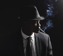 Image showing Man, gangster and cigarette in studio by dark background with smoke, silhouette and dangerous in shadow. Mafia, secret agent or male in night for smoking with vintage aesthetic by black backdrop