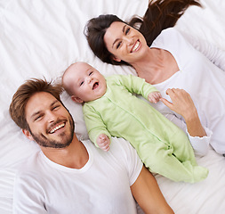 Image showing Above, portrait and happy parents with baby on bed for love, care and quality time together at home. Smile of mother, father and family with cute newborn kid relax in bedroom, support and happiness