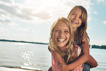 Image showing Family, children and a mother with her daughter on the beach during summer for bonding on vacation. Portrait, love and kids with a woman carrying a female child on her back on the coast by the ocean