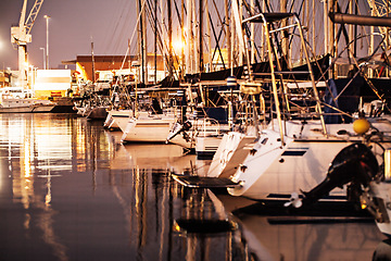 Image showing Boat, sunset and yacht on water in harbor for traveling, luxury cruise and sea transport at night. Transportation, marine vessel and boating club port for adventure, journey and sailing on ocean