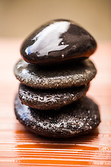 Image showing Stones, zen and wet rocks for hot stone massage at a spa for luxury and wellness. Peace, closeup and rock balance with tranquility and feng shui for meditation, holistic therapy and water on pile
