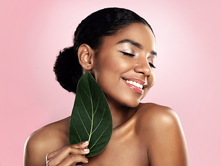 Image showing Happy woman, green skincare and natural leaves in studio, pink background or eco friendly aesthetic cosmetics. Face, african model and beauty from plants, leaf and sustainability of vegan dermatology