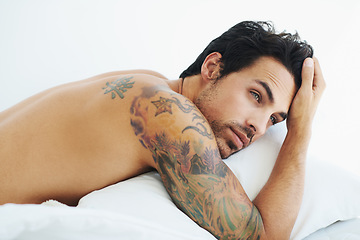 Image showing Thinking, relax and sexy with a topless man on a bed, lying in studio on a white background. Tattoo, idea and shirtless with a handsome young male model posing in a bedroom for sensuality or desire