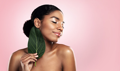 Image showing Happy woman, leaf and natural beauty in studio, pink background and mockup for aesthetic cosmetics. Face, african model and skincare from plants, green leaves and sustainability of vegan dermatology