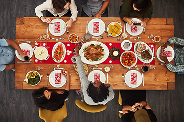 Image showing Thanksgiving, overhead and friends sitting around a table for a food meal during a celebration event. Family, roast or nutrition with a man and woman group in the living room for a social gathering