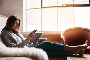 Image showing Relax, tablet and credit card with a woman banking online on a sofa in the living room of her home. Ecommerce, financial freedom and shopping with a young female customer or consumer in her house