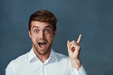 Image showing Portrait, wow and idea with a man pointing in studio on a blue background during a lightbulb moment. Face, surprise and eureka with an excited young male person looking shocked or amazed by good news