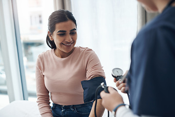 Image showing Blood pressure, woman and health check with a smile at a clinic and healthcare hospital with doctor. Monitor, checking and nurse with young female patient at a wellness and medical consultation