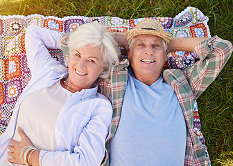 Image showing Portrait, picnic and an elderly couple lying on a blanket in a field together for romance or bonding from above. Relax, smile and retirement with happy seniors outdoor in the countryside for dating