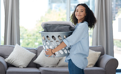 Image showing Portrait, laundry and spring cleaning with a woman in the living room of her home carrying a basket. Happy, smile and housework with a young female cleaner carrying fresh washing in her apartment