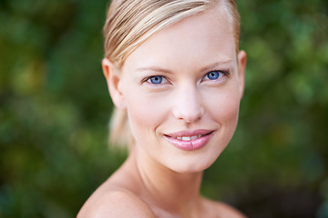 Image showing Portrait, beauty and blue eyes with a woman outdoor on a green background in nature for skincare. Face, spring and smile with an attractive young female model posing outside in a natural environment