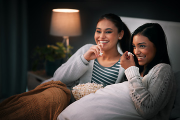 Image showing Laughing, popcorn and women watching tv, movies or show at home for sleepover with streaming service and comedy. Gen z people relax in bedroom with funny TV film, cinema subscription and internet