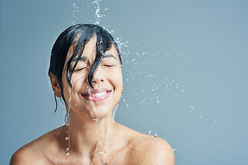 Image showing Shower, beauty and face of woman with water in studio on blue background for wellness, cleaning and grooming. Skincare, bathroom and female person with splash for washing hair, body and cleansing