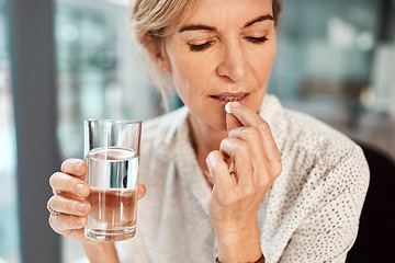 Image showing Pill, water and senior woman drinking medicine or supplements for illness or health care in her office. Medical, drugs and sick elderly female person healing and drink tablet or vitamin