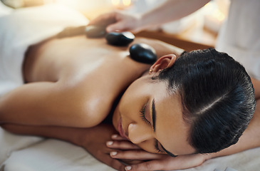 Image showing Woman, relax and sleeping for back massage, skincare or relaxation at indoor beauty spa on bed. Female relaxing with hands of masseuse applying hot rocks for physical therapy or treatment at resort