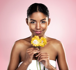 Image showing Portrait, woman and flowers for skincare in studio, pink background and eco friendly cosmetics. Face, african model and natural beauty with yellow daisy, plants and sustainability for floral blossom