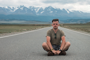 Image showing man sitting on road in Altai mountain.