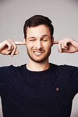 Image showing Block sound, man and finger in ears of a person loud music problem in a studio. Frustrated, isolated and grey background of a male model pain with closed ear from noise for silence and peace