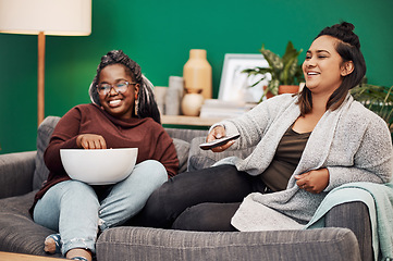 Image showing Girl friends, watching tv and home living room laughing on a couch with a happy smile. Series, funny movie and women together in a lounge with a friend looking at a television in house with popcorn