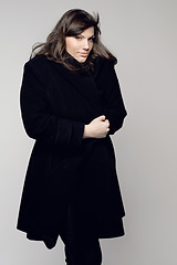 Image showing Woman, fashion and portrait of plus size model posing in winter clothing against a grey studio background. Isolated female person standing with stylish black coat, body or warm fashionable clothes