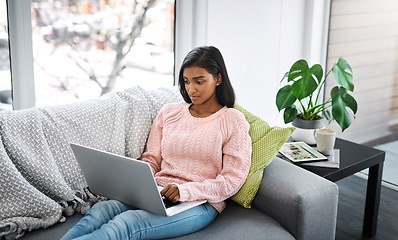 Image showing Woman, laptop and typing on home sofa for student research, streaming or social media. Indian female person on a couch to relax, surfing internet or writing email for communication on website