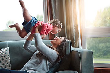 Image showing Mom, happy and lifting girl on sofa in home living room and relax, bonding and quality time together or mother, love and family happiness. Child, mommy and playing game on couch in house with smile