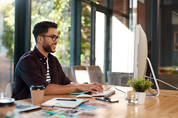 Image showing Office, designer and man typing on computer at desk while online for search or creative work. Happy male entrepreneur person with internet connection and glasses for design project or writing email