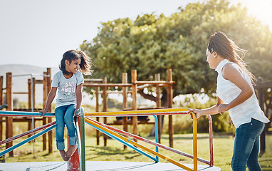 Image showing Mom with daughter on roundabout at park, playing together with smile and fun outdoor. Love, care and bonding with happy family in nature, woman and girl enjoying time at playground with freedom