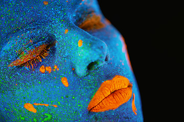 Image showing Neon paint, makeup and woman face closeup with dark background and creative cosmetics. Surreal glow, fantasy and psychedelic cosmetic of a female model with unique and creativity art in studio