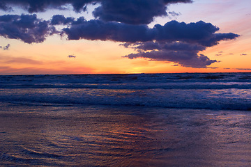 Image showing Nature, ocean and peace with sunset at beach for landscape, summer break and vacation travel. Cloud, waves and environment with sunrise at coastline for sea holiday, calm horizon and seascape