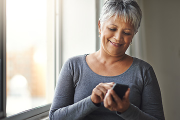 Image showing Window, typing and senior woman with a cellphone, social media and mobile app at home. Mature female, happy model and old lady with a smartphone, email and happiness with network and online reading