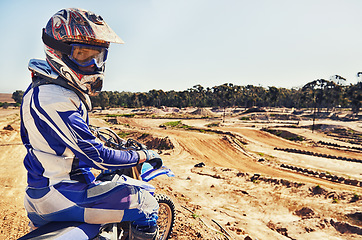 Image showing Portrait, motorcycle and man on a dirt track for action, competition or a sports race outdoor. Ride, bike and power with a male athlete sitting on a motorbike for training, practice or preparation