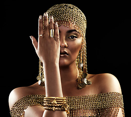 Image showing African woman, portrait and gold jewelry with beauty and cosmetics in a studio. Isolated, black background and young female queen with crown, Egypt fashion and style with hand over face