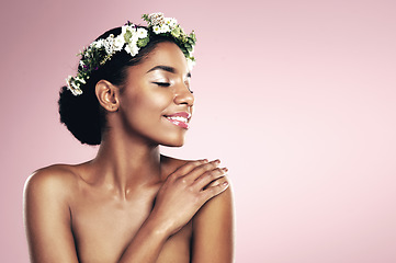 Image showing Woman, flower crown and natural beauty in studio, pink background and aesthetic plants with mockup. Happy african model, skincare and floral wreath in hair for sustainable cosmetics, shine and glow